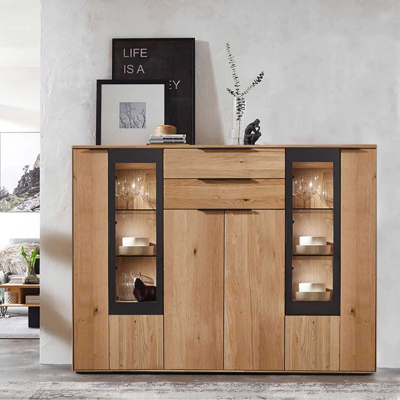 WM-1910-4740-amiente Modernes Highboard aus Wildeiche mit rechts und links Vitrinenfächern abgesetzt it carbonfarbigen Metallrahmen, als Ambiente Bild