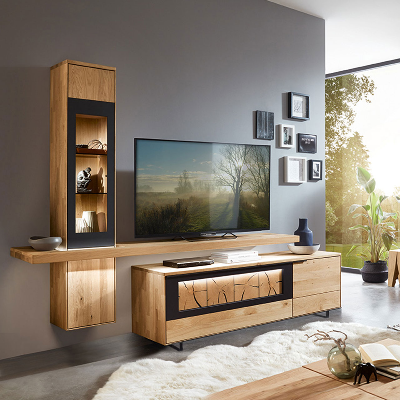 Wohnzimmer Type 0104F bestehend aus einem TV-Hängeelement als Vitrine in Wildeiche und einem mittig angebrachten Board für den Fernseher, kombiniert mit einem Lowboard in Wildeiche und Hirnholz Akzent mit Kufen.