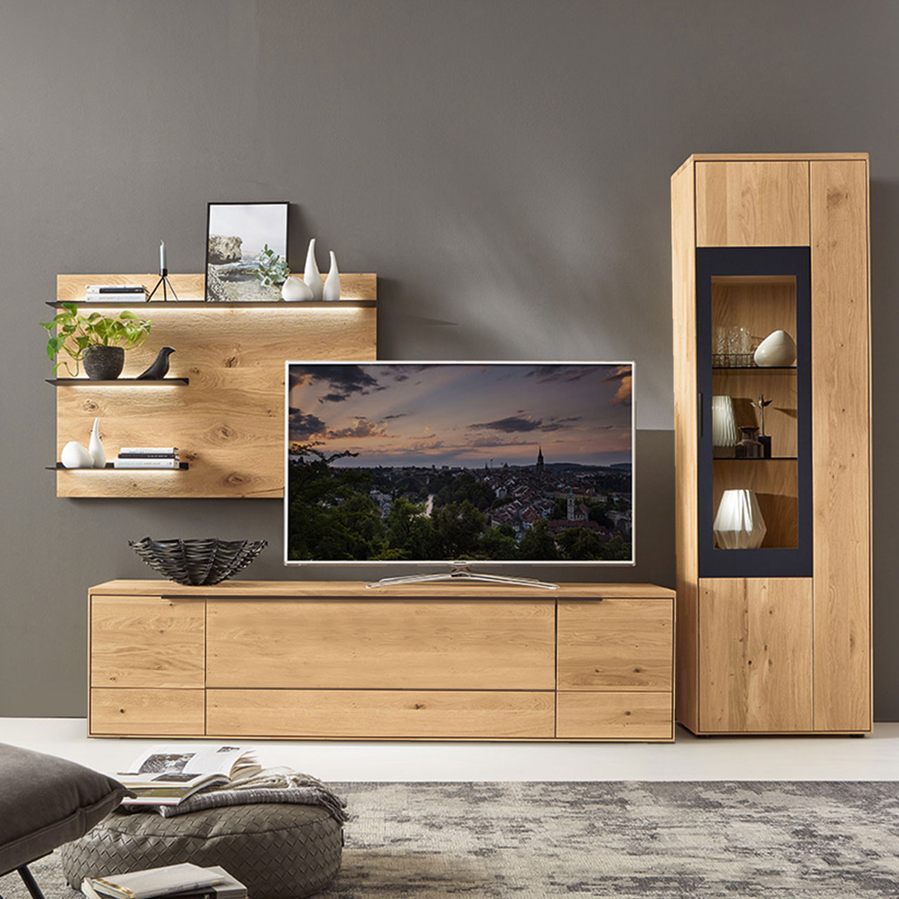 Wohnzimmer Type 0109G, bestehend aus einem Zeilenschrank mit Vitrinenfach mit einem carbonfarbigen Metallrahmen, kombiniert mit einem Wandboard und einem Lowboard in Wildeiche.
