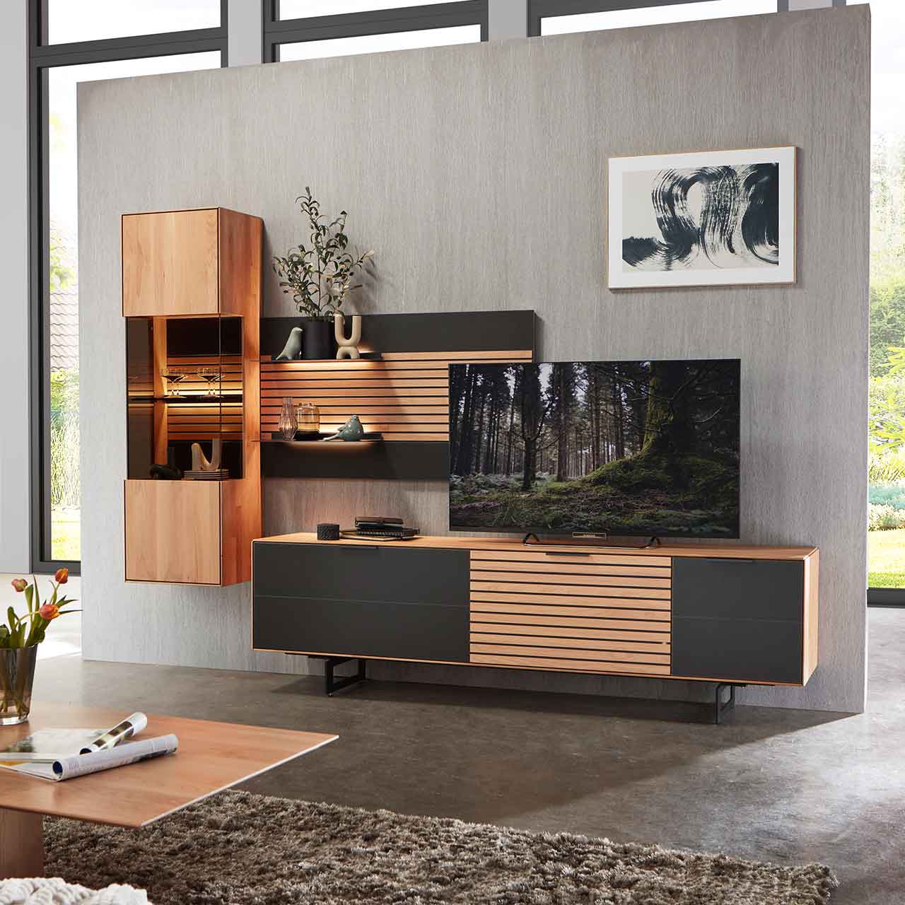 WM2320-Paneel-8224-Erle-Mattglas-Ambiente WM 2320 Paneel Wandboard 8224 in Erle, mit Lamellen, schwarzer Mattglas Akzent- und zwei Ablagen. In einer Wohnwand dargestellt.