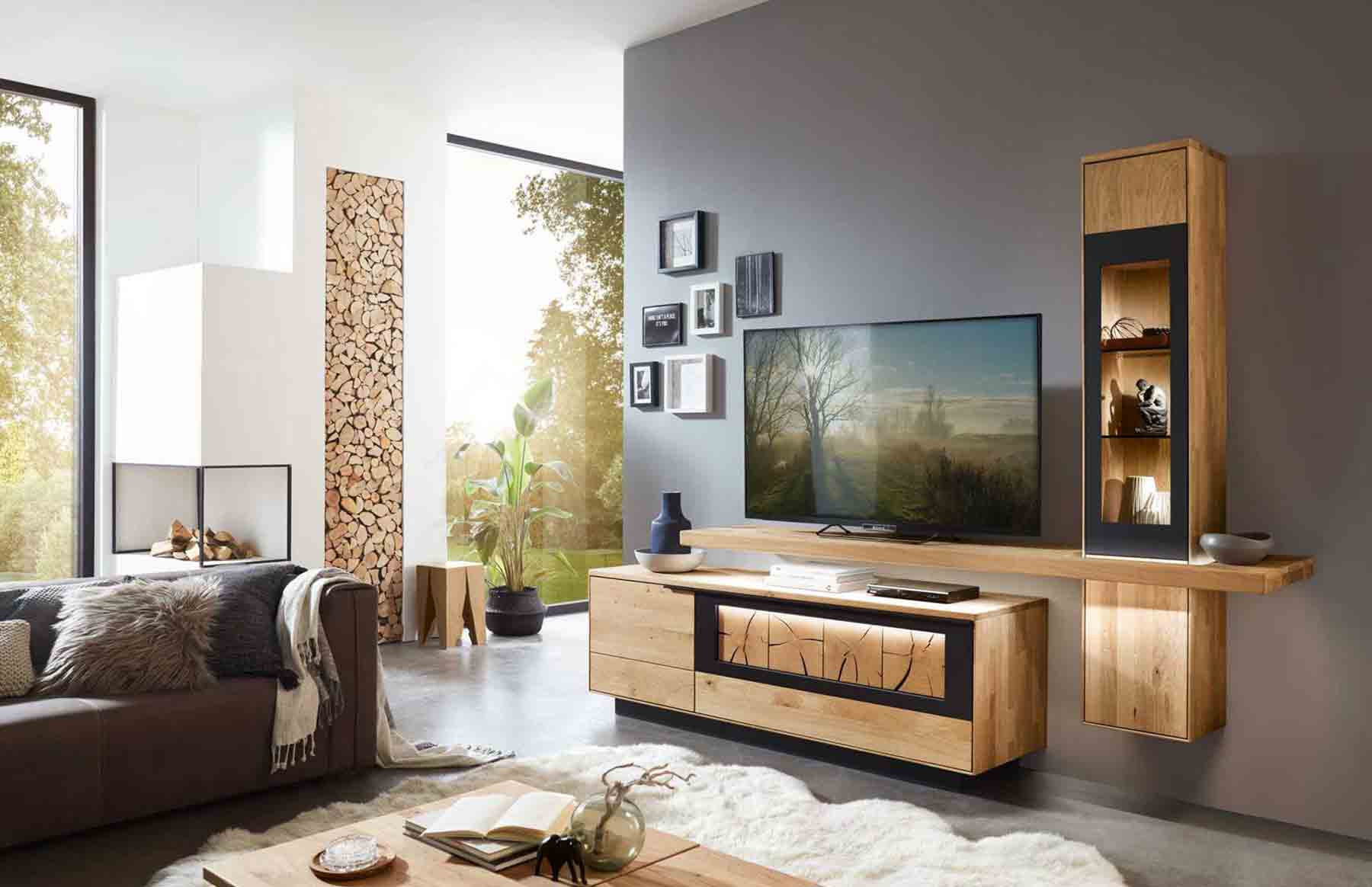 Wohnzimmer WM 1910 Hier werden Sie direkt zur WM 1910 Kategorie weitergeleitet. Kachel zeigt ein TV-Hängeelement als Vitrine in Wildeiche und einem mittig angebrachten Board für den Fernseher, kombiniert mit einem Lowboard in Wildeiche mit Kufen und Hirnholz Akzent.