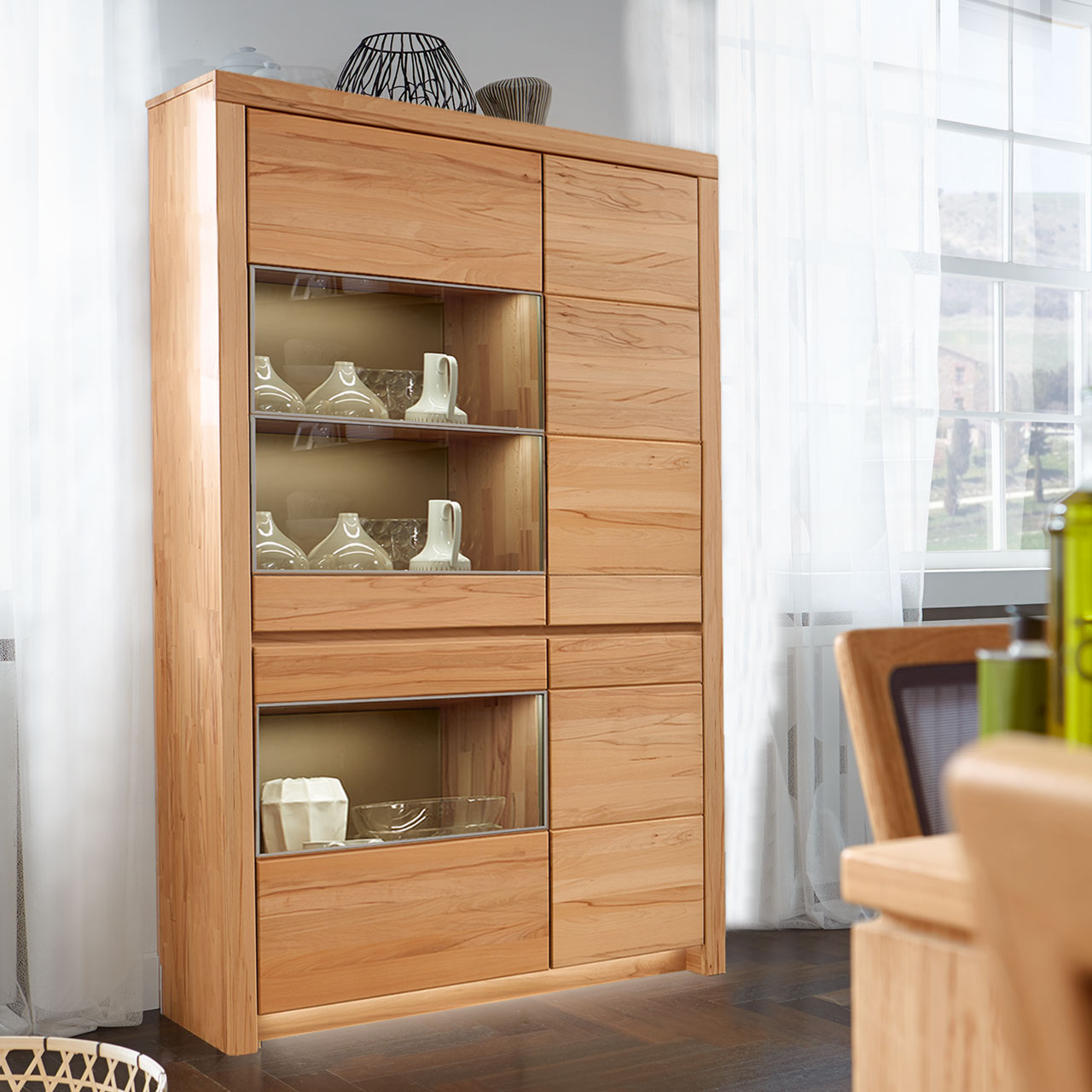 Soleo-3000-Zeilenschrank-5103-ambiente-Kernbuche SOLEO 3000 Zeilenschrank Type 5103 in massiver Kernbuche, mit zwei Holztüren und zwei Türen mit Vitrinenfach untereinander angeordnet, als Ambiente Bild.