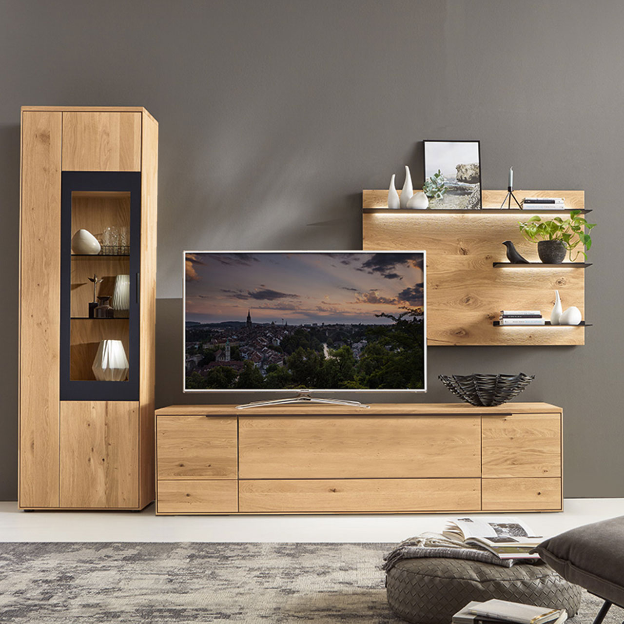 WM 1910 Wohnzimmer ype 0009G Ambiente Wohnzimmer Type 0009G bestehend aus einem Zeilenschrank mit Vitrineneinsatz in Wildeiche abgesetzt mit einem carbonfarbigen Metallrahmen, kombiniert mit einem Wandpanee und einem Lowboard in Wildeiche.