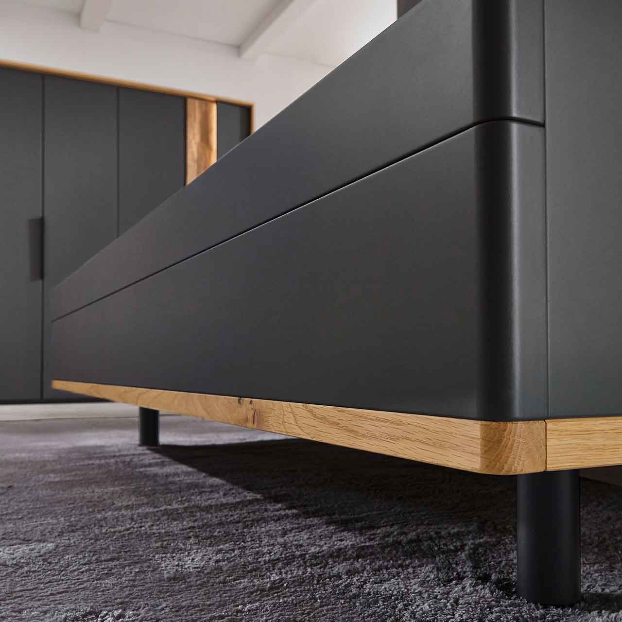WSL 8800 Bett Detailansicht Bett Detailansicht, seitlich das Bett hat abgerundete Kanten in Lack graphitgrau kombiniert mit Wildeiche Akzent im unteren Bereich als Abschlusskante.