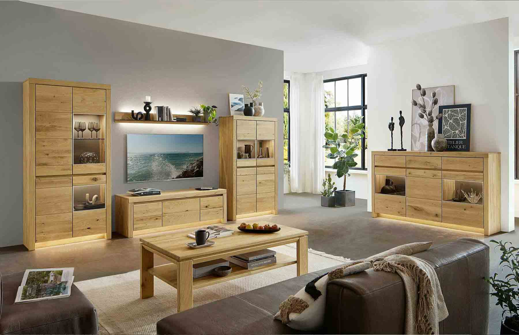 Wohnzimmer Soleo 3000 Hier werden Sie direkt zur Soleo 3000 Kategorie weitergeleitet. Kachel zeigt ein Wohnzimmer in Wildeiche, bestehend aus einem Zeilenschrank, Highboard, Sideboard mit Vitrinenfach, kombiniert mit einem Lowboard und einem rechteckigen Holztisch.
